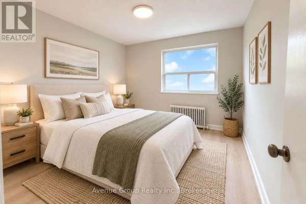 Another view of the bedroom showing the bed, nightstands, and a window with a view. - 311 - 1053 Don Mils Road, Toronto