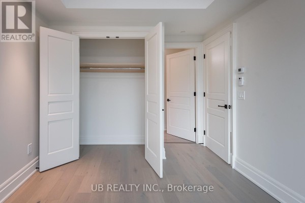 Bedroom with double doors opening into a walk-in closet and light grey wood flooring. - 311 - 1451 Wellington Street W, Ottawa