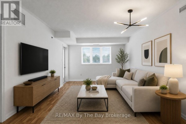 Empty room with white walls, wood laminate flooring, a window, and a chandelier. - 311 - 16 Westbury Road, Wasaga Beach