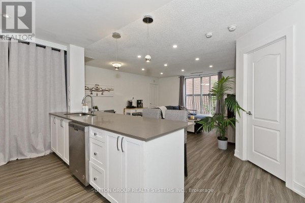 Open-concept living area with a kitchen island, dining table, and seating area. - 311 - 4198 Dundas Street W, Toronto