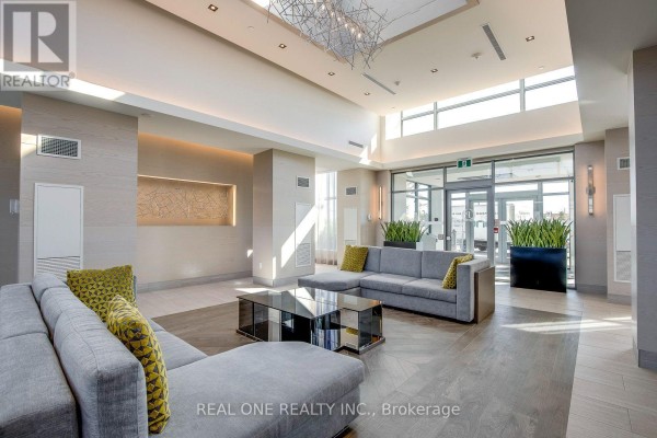 Spacious condominium lobby with sectional sofas, glass coffee table, modern chandelier, and large windows. - 311 - 4633 Glen Erin Drive, Mississauga