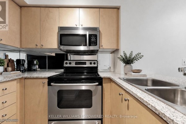 Kitchen with light wood cabinets, granite countertops, stainless steel appliances, and a double sink. - 311 - 8 Scollard Street, Toronto