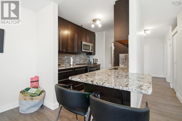 Interior kitchen view with dark wood cabinets, granite countertops, stainless steel appliances, and a breakfast bar. - 311-41 Moirs Mill Road, Bedford
