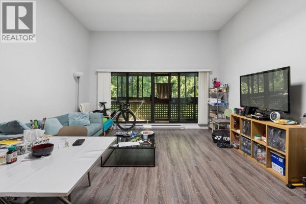 Living room with sofa, dining area, television, large glass doors, and wood-look floor. - 311 444 W 49th Avenue, Vancouver