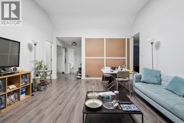 Living room and dining area with light blue sofa, table, television, and wood-look floor. - 311 444 W 49th Avenue, Vancouver