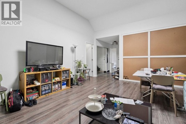Living room with a television, sofa, dining table, and wood-look flooring. - 311 444 W 49th Avenue, Vancouver