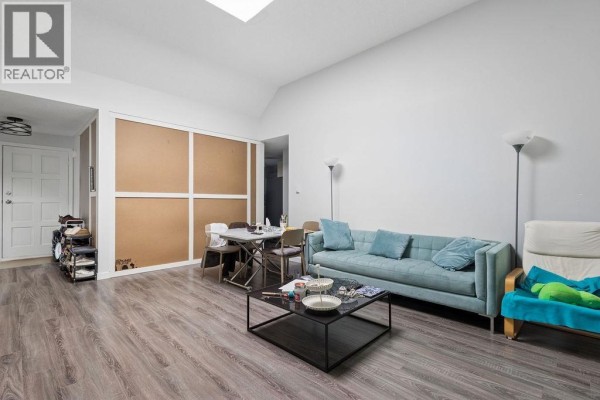 Living room with a sectional sofa, dining table, and large window with access to balcony. - 311 444 W 49th Avenue, Vancouver