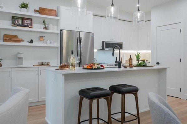 Kitchen island with black stools, stainless steel refrigerator, and white cabinets. - 311 46187 Thomas Road, Vedder Crossing, Chilliwack
