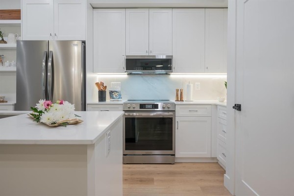White kitchen with stainless steel appliances, island, and modern cabinetry. - 311 46187 Thomas Road, Vedder Crossing, Chilliwack