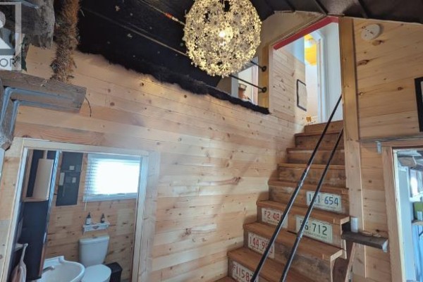 Kitchen with dark cabinets and an island, adjacent to a hallway with rustic wood paneling. - 311 47 Avenue W, Claresholm