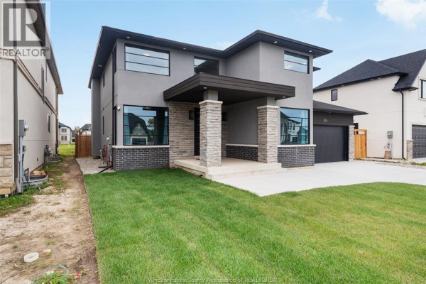 View of the front of a modern house with a gravel driveway and surrounding homes. - 311 Benson Court, Amherstburg