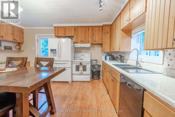 Kitchen with wood cabinets, white appliances including a refrigerator and stove, and a dining table. - 311 Fourth Street W, Cornwall