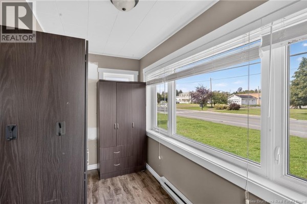 Living room with a brown leather sofa, television, and dark wood flooring. - 311 Principale Street, Eel River Crossing