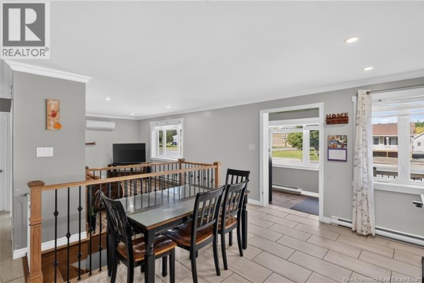 Open concept dining area and kitchen with grey walls and wood cabinetry. - 311 Principale Street, Eel River Crossing