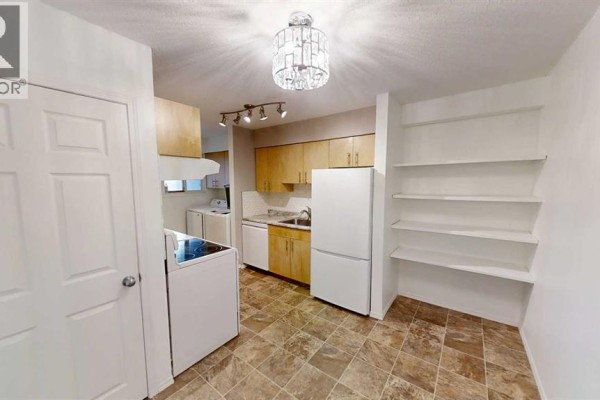 Kitchen with wood cabinets, white appliances, tiled flooring, and white shelving. - 3110, 7201 Poplar Drive, Grande Prairie
