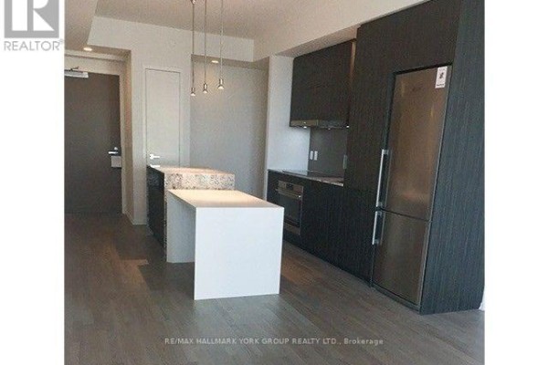 Modern kitchen with dark cabinets, stainless steel appliances, and an island with a white countertop. - 3112 - 1 Bloor Street E, Toronto