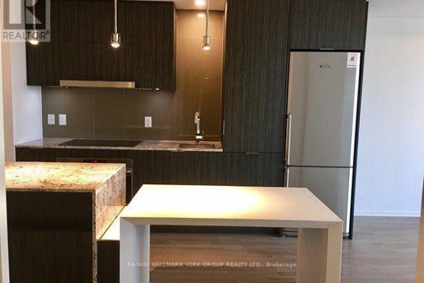 Close-up of the kitchen island with granite detailing and modern pendant lights above. - 3112 - 1 Bloor Street E, Toronto