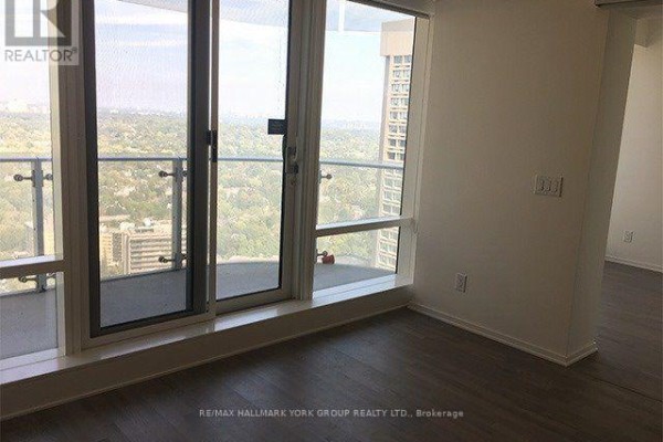Living area with floor-to-ceiling windows and glass balcony doors overlooking a cityscape. - 3112 - 1 Bloor Street E, Toronto