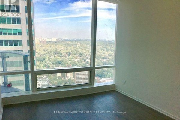 View of the city skyline through large windows in a room with light-colored walls. - 3112 - 1 Bloor Street E, Toronto