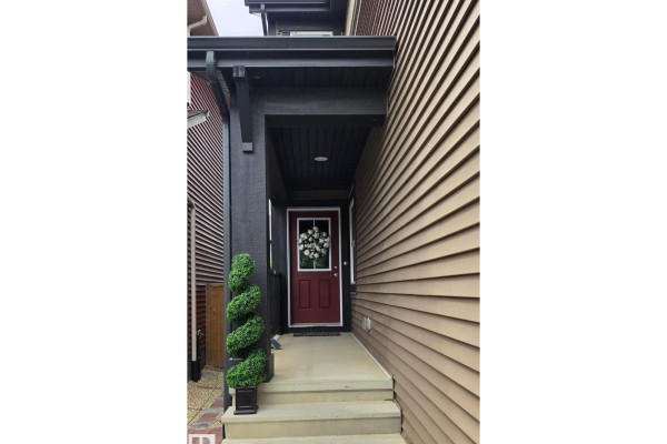 Rear exterior view of a tan house with a sliding glass door and wooden fenced backyard. - 3114 Chokecherry Bend Sw, Edmonton