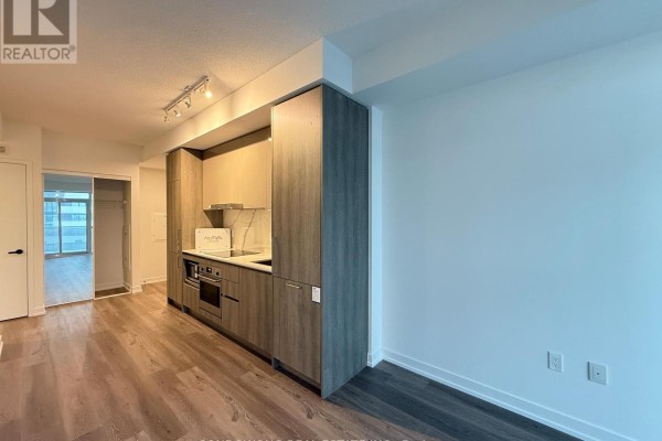 Apartment kitchen with dark wood cabinets, stainless steel appliances, and dark wood floors. - 3115 - 225 Commerce Street, Vaughan