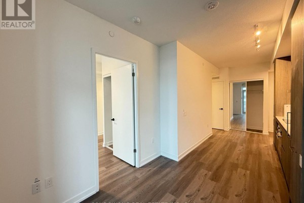 View of apartment hallway showing open doors to rooms and dark wood flooring. - 3115 - 225 Commerce Street, Vaughan