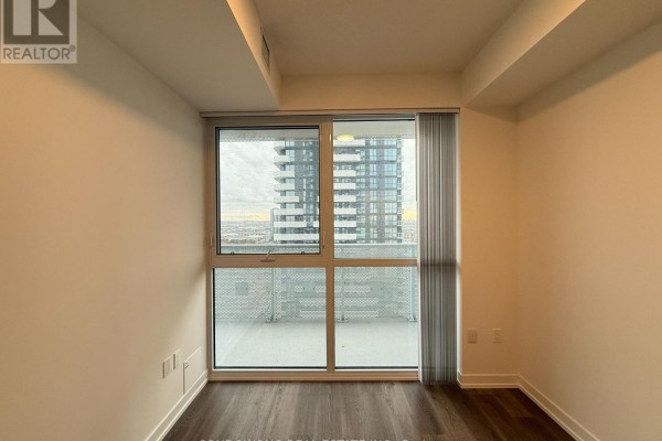 Room with balcony access and large window overlooking city buildings and a balcony. - 3115 - 225 Commerce Street, Vaughan