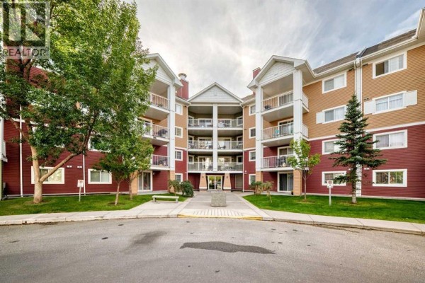 Apartment building exterior view from paved driveway with landscaping. - 3116, 10 Prestwick Bay Se, Calgary