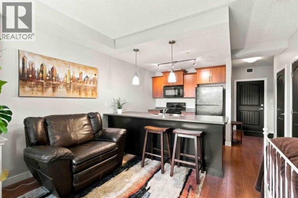 Living area with a leather sofa, island with bar stools, and kitchen cabinets. - 3117, 135c Sandpiper Road, Fort Mcmurray