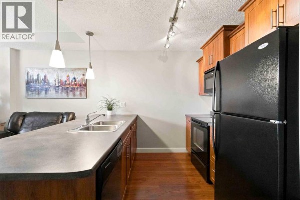 Kitchen area with wood cabinets, black appliances, and a large island with sink. - 3117, 135c Sandpiper Road, Fort Mcmurray