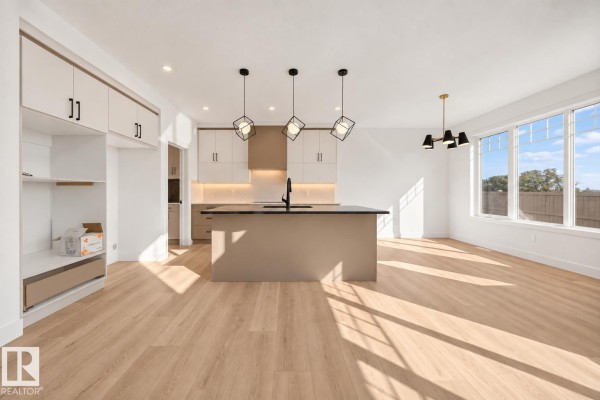 Spacious living room with vaulted ceilings, a black fireplace, light wood floors, and carpeted stairs. - 3119 9 St Nw, Edmonton
