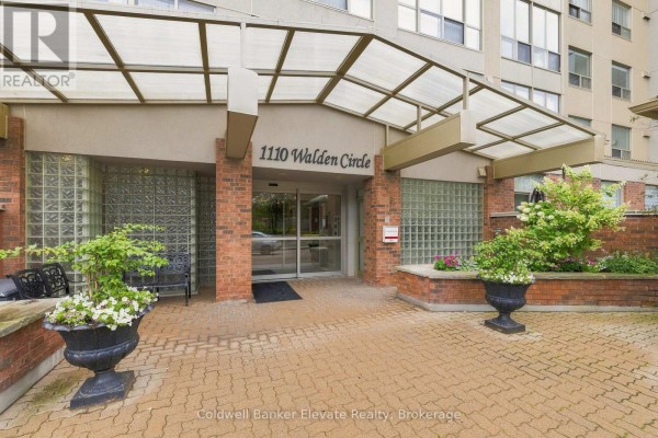 Entrance to the apartment building with brick pillars, glass blocks, and paved walkway. - 312 - 1110 Walden Circle, Mississauga