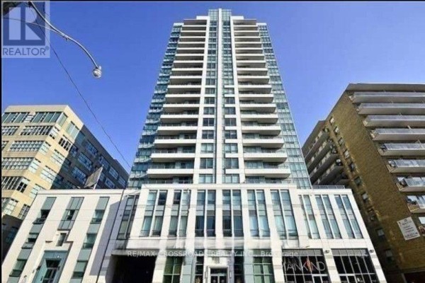 Tall apartment building facade with balconies against a bright blue sky. - 312 - 212 Eglinton Avenue E, Toronto