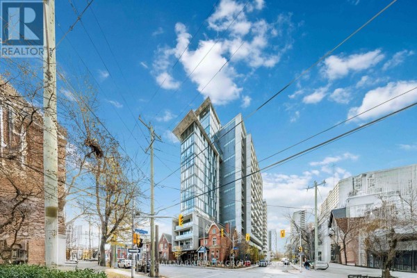 Street view of a contemporary apartment building with glass facade and surrounding brick buildings. - 312 - 224 Lyon Street N, Ottawa