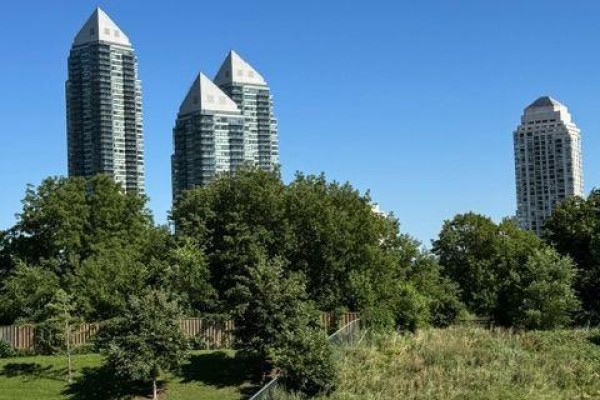 Street view of condo buildings with parking area and fence. - 312 - 251 Manitoba Street, Toronto