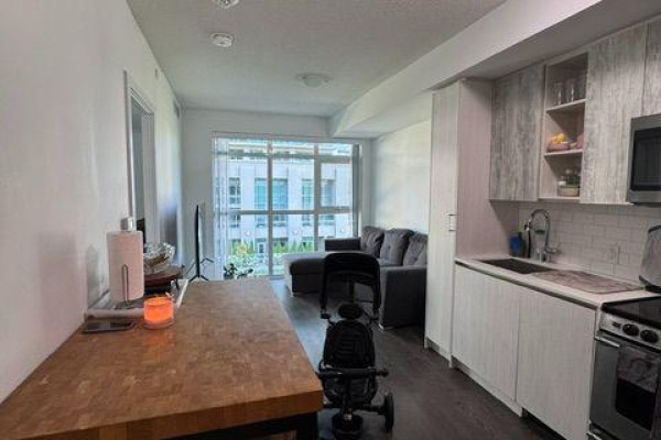 Kitchen and living area with dining table and high chair. - 312 - 251 Manitoba Street, Toronto