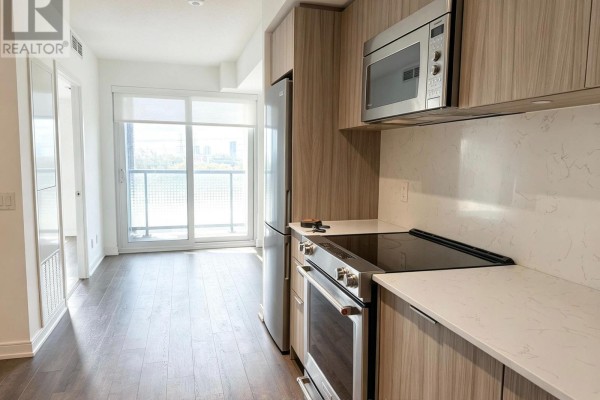 Apartment kitchen area with stainless steel appliances, light wood cabinetry, white countertops, and view of living space. - 312 - 30 Samuel Wood Way, Toronto