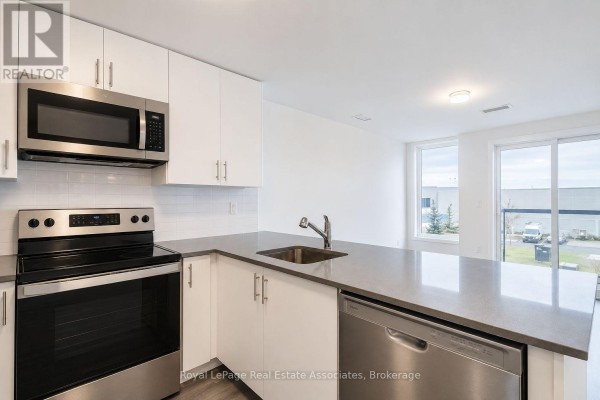 White kitchen with stainless steel appliances, grey countertops, and white cabinetry. - 312 - 3401 Ridgeway Drive, Mississauga