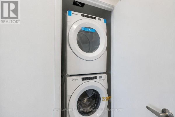 Stacked white front-loading washer and dryer units in a closet. - 312 - 3401 Ridgeway Drive, Mississauga
