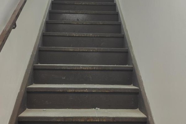 View looking up a dark carpeted staircase with a metal handrail against a light-colored wall. - 312 - 9011 Leslie Street, Richmond Hill