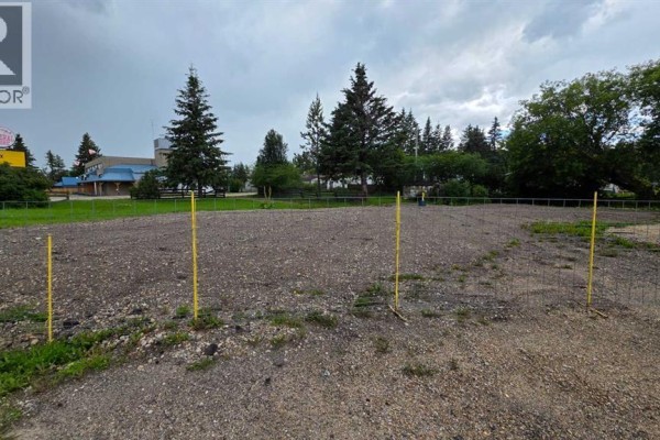 Gravel lot bordered by temporary fencing with surrounding trees and commercial buildings in the distance. - 312 3rd Street, Blue Ridge