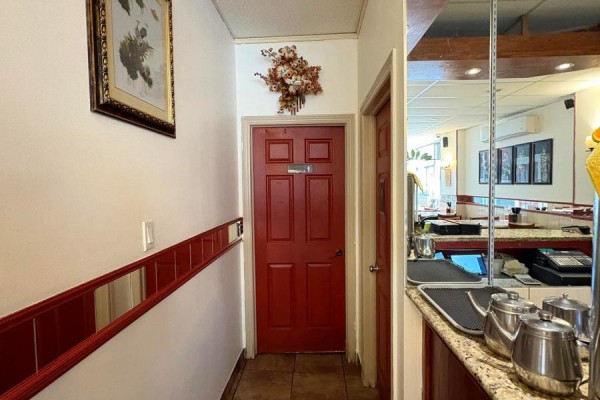 Interior hallway with a red door, artwork on the wall, and a mirrored wall reflecting restaurant seating. - 312 Bank Street, Ottawa