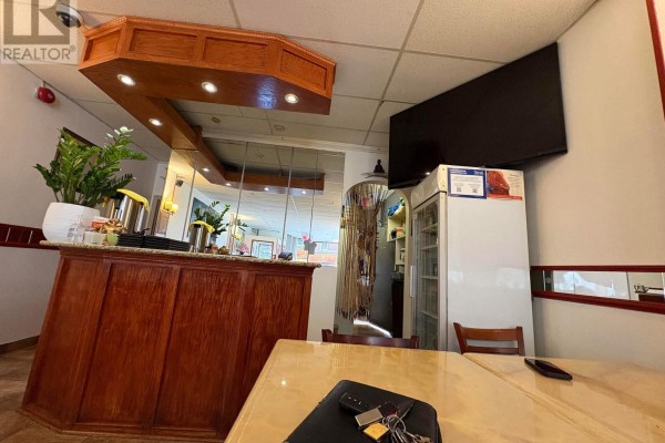 Interior view of a restaurant counter with wooden cabinets, granite countertop, and a flat-screen TV mounted on the wall. - 312 Bank Street, Ottawa