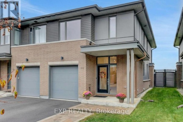 Front exterior of a townhouse with brick and grey siding, showing a covered entryway and a single garage door. - 312 Squadron Crescent, Ottawa