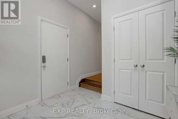 Interior hallway with white walls, marble-look tile floor, a closed door, and stairs leading up to the right. - 312 Squadron Crescent, Ottawa