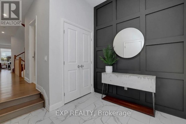Hallway interior with a decorative black wall panel, a round mirror, a console table, and a staircase on the left. - 312 Squadron Crescent, Ottawa