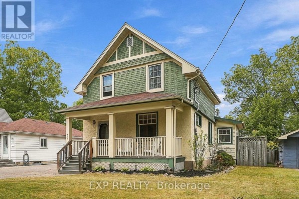Front view of a house with green shingled upper level and stucco lower level, and a porch. - 312 Walnut Street W, Whitby