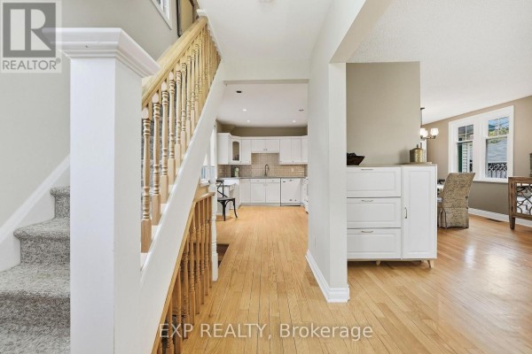 Interior view of a house foyer with hardwood floors, a staircase, and an open view to the kitchen. - 312 Walnut Street W, Whitby