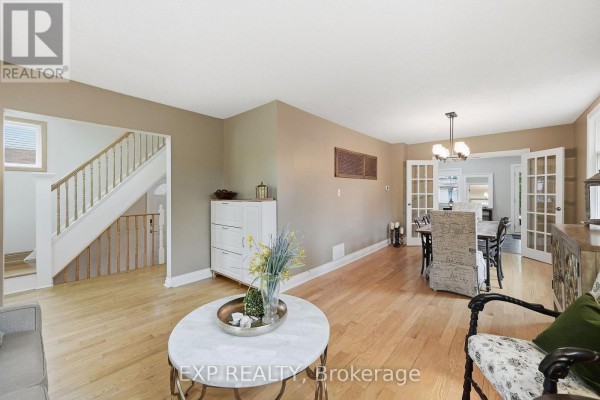 Open-concept living and dining area with hardwood floors, a staircase, and French doors leading to another room. - 312 Walnut Street W, Whitby