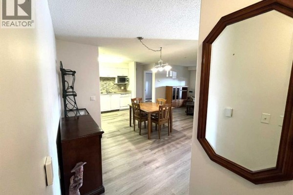 Hallway leading to the dining area, kitchen, and living room with a decorative mirror on the wall. - 3120, 3000 Millrise Point Sw, Calgary